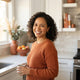 A friendly, diverse woman smiling in a brightly lit kitchen setting, representing a satisfied customer.
