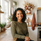 A friendly and diverse woman smiling in a bright, modern kitchen, symbolizing a satisfied and happy customer.